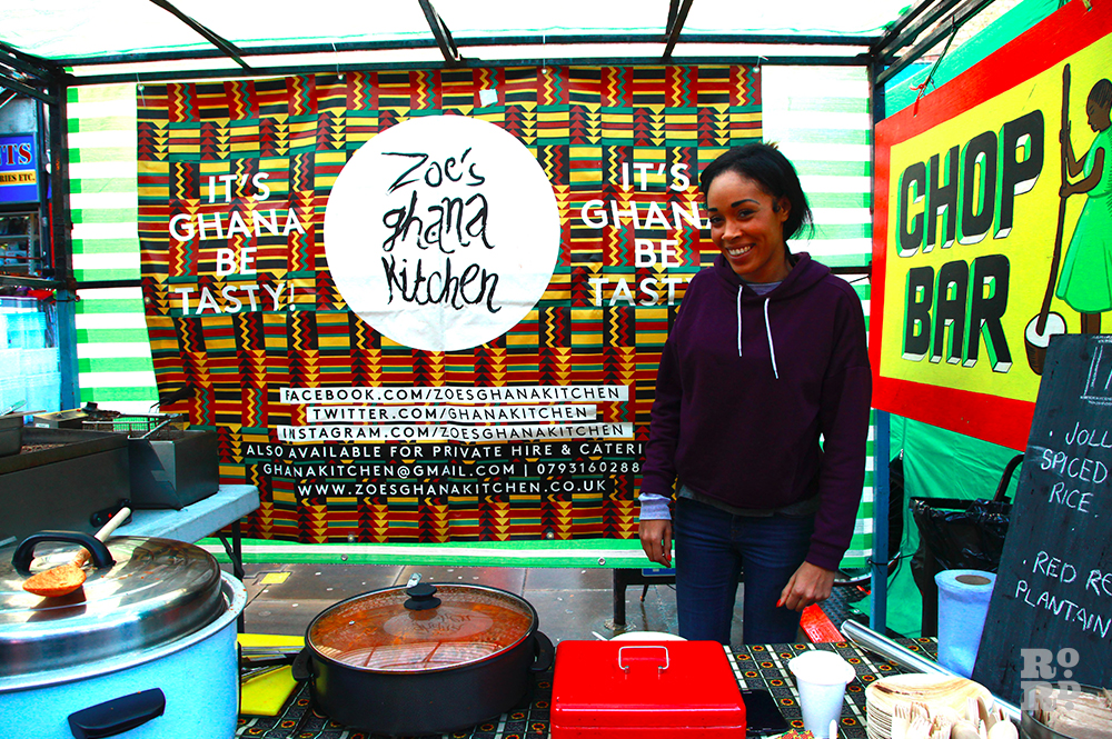 Street food stall with woman smiling and standing in front of African print fabric