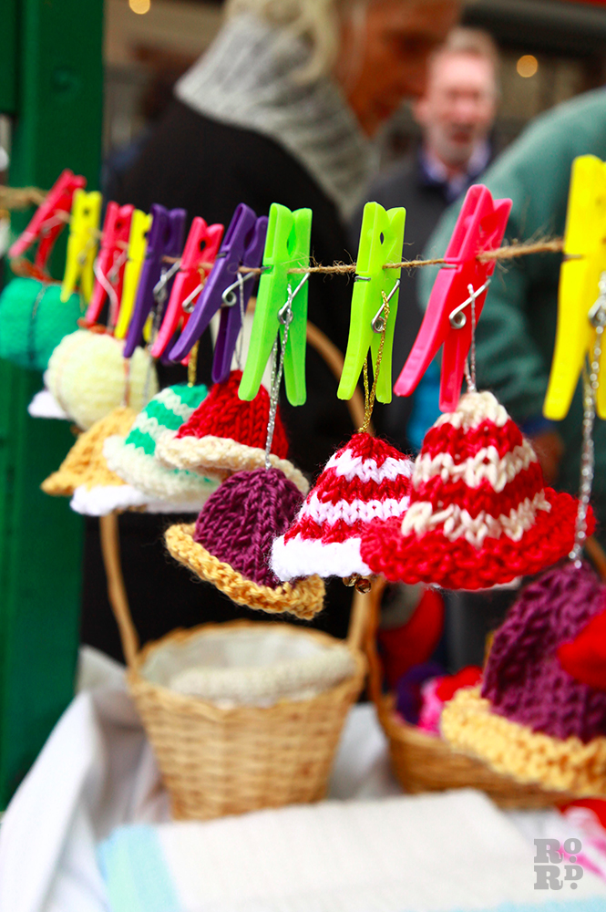 Knitted egg cosies hanging on line with colourful clothes pegs.