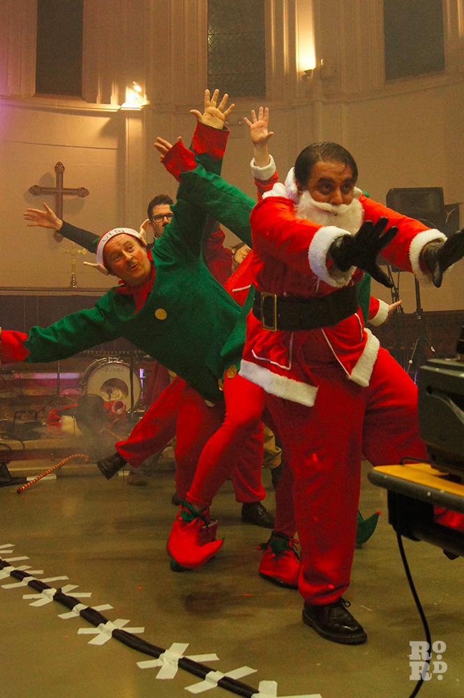 Cabaret dance featuring men dressed as father christmas and elves, performing in a church.