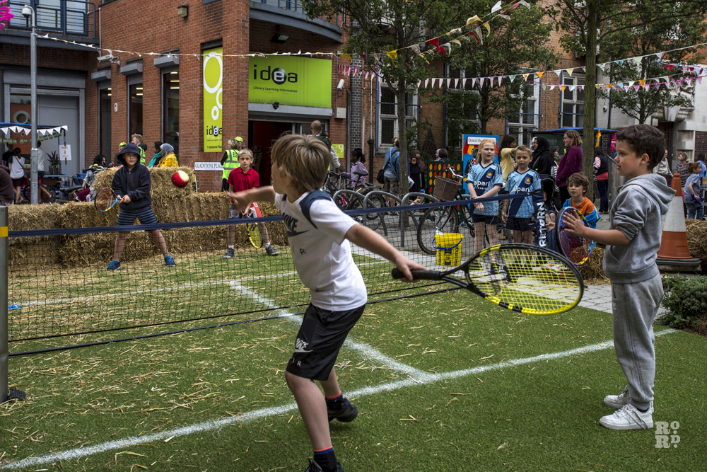 Children playing tennis on artificial lawn in urban setting
