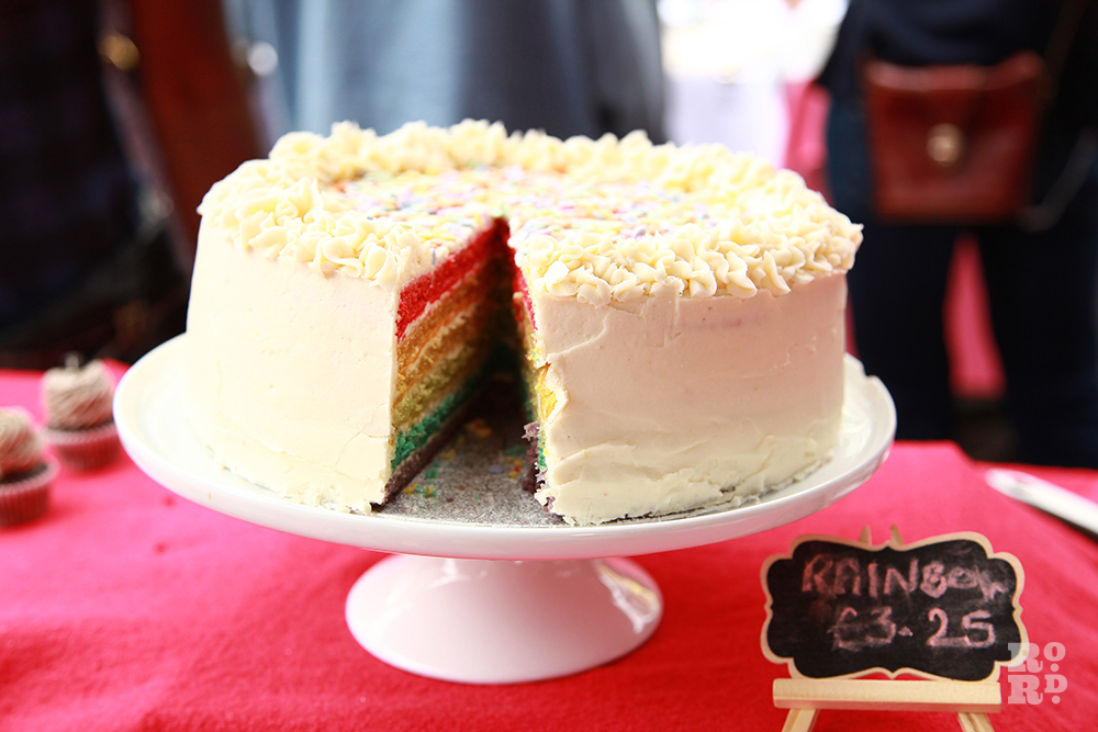 Cake on a stand with rainbow layers and butter icing