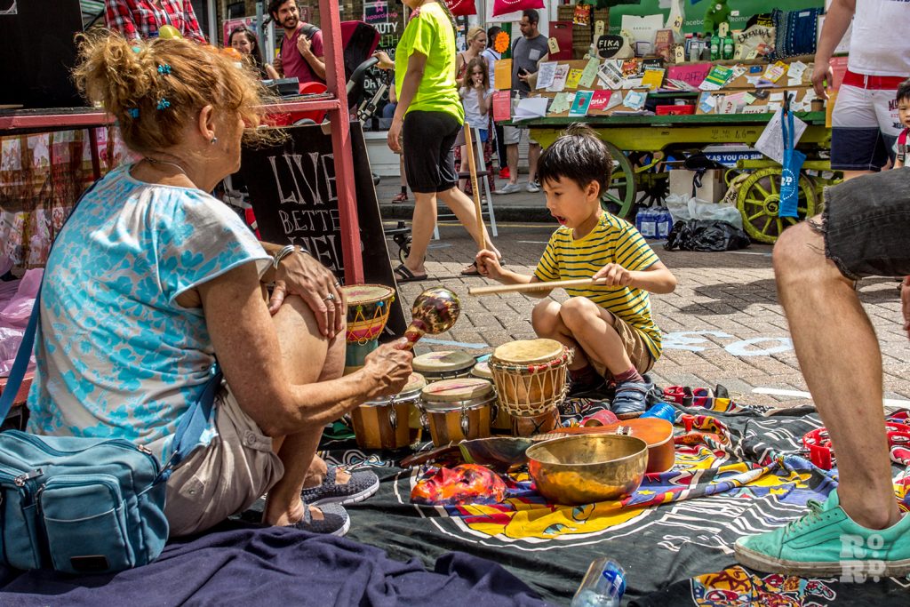Young child playing tribal drums on the street at Roman Road Summer Festival