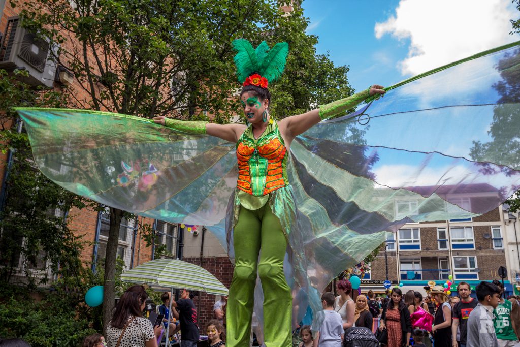 Slilt walker in green fairy outfit with wings spread at Roman Road Summer Festival 2016