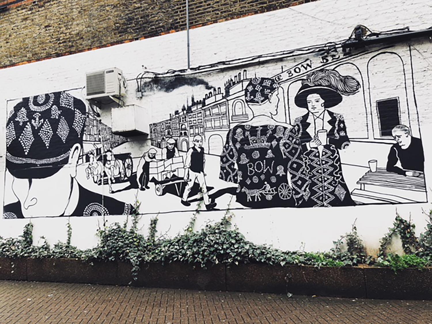 Black and white mural of pearly kings and queens on a wall near Bow Bells, East London