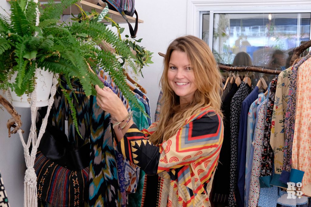 A designer stands by some of her brightly coloured and patterned clothes