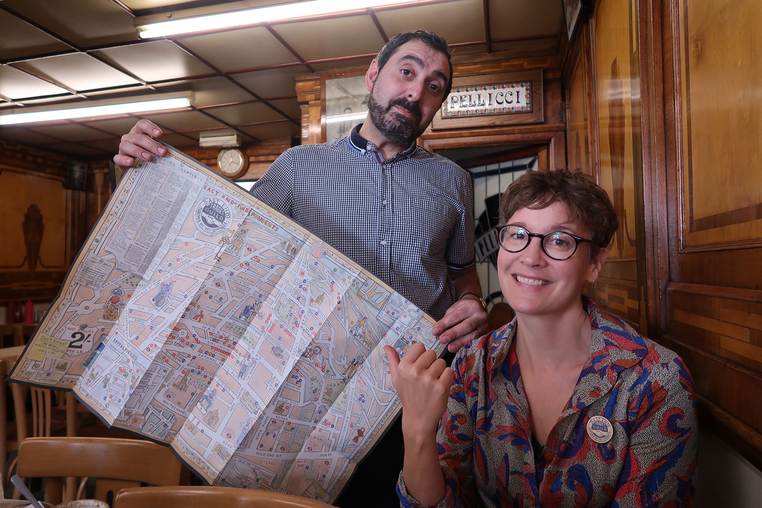 A man and a woman in a beautiful cafe display a map
