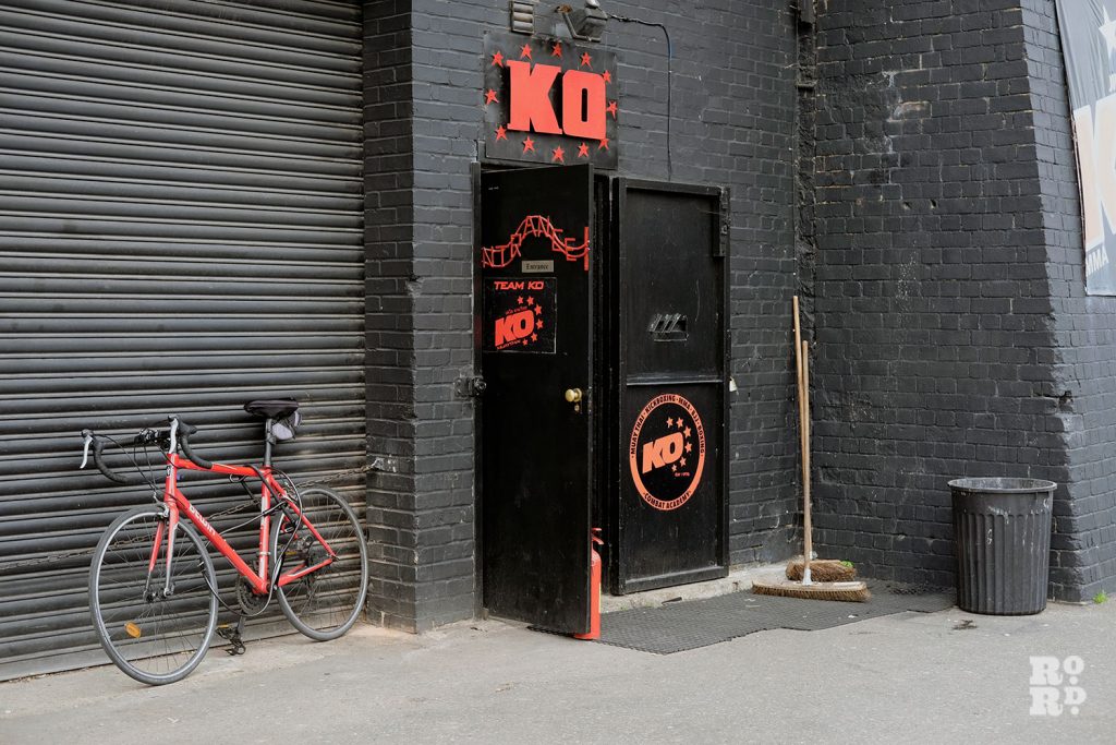 The entrance of KO Boxing, red logo on black painted brick walls of railway arch