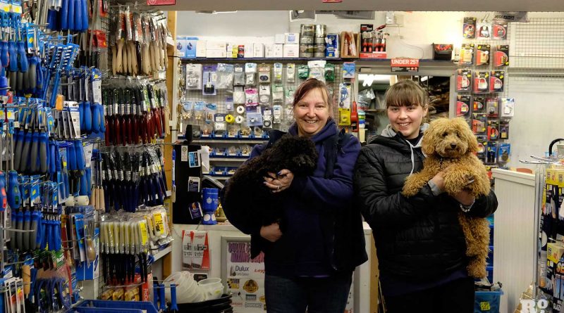 Annie and Katie holding their dogs at Thompsons DIY hardware store, Roman Road, Bow, East London.