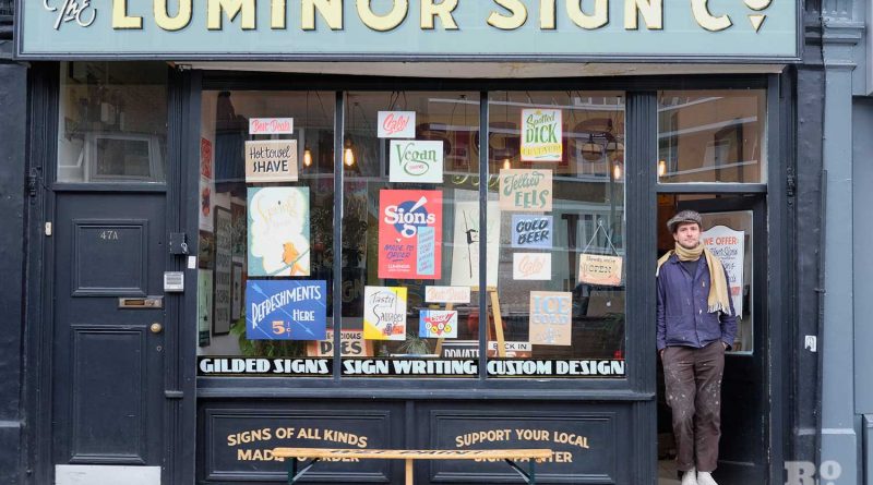 Ged Palmer, standing in the doorway of his shop on Roman Road Luminor Sign Co