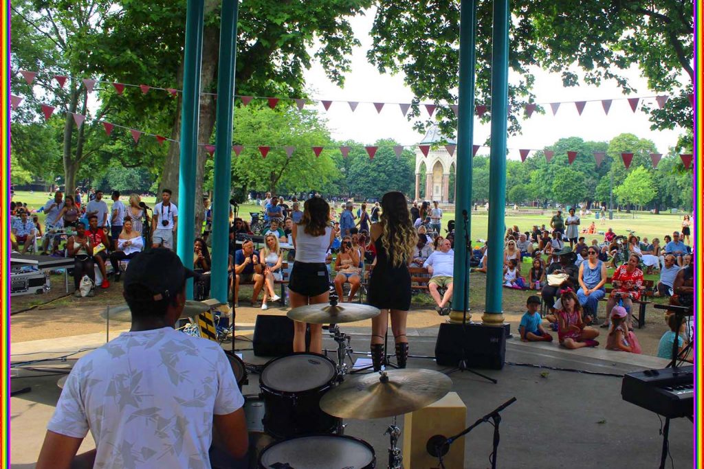 People enjoying music at bandstand of Victoria Park, where the Pride Picnic is held