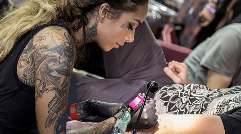 Dark haired lady tattooing at London Tattoo Convention