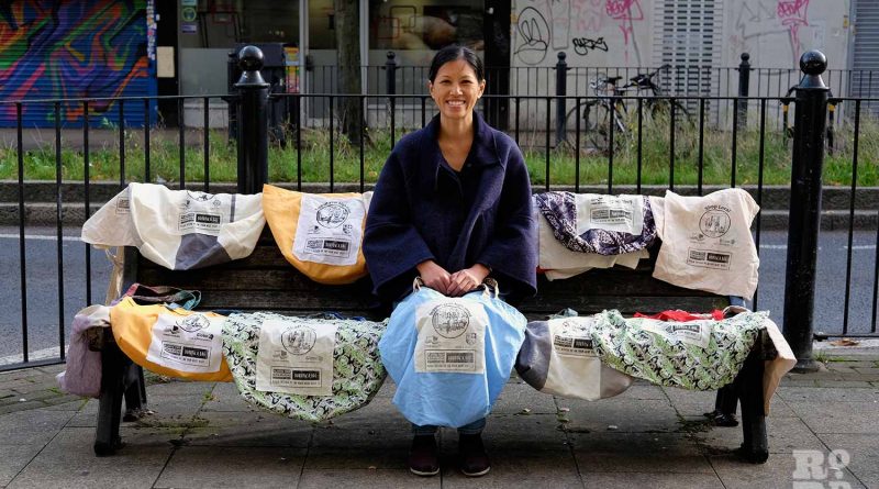 Linda Tai sits with the Roman Road borrow-a-bag tote bags