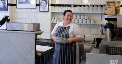 G.Kelly pie and mash Roman Road staff member holding stack of dishes