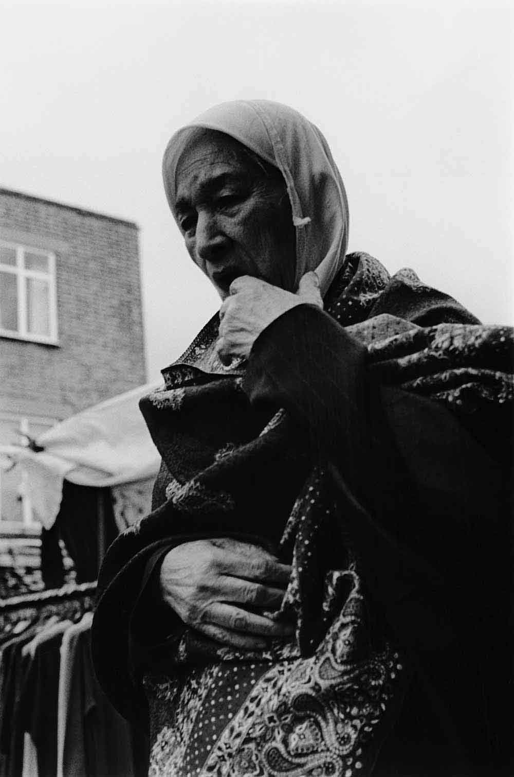 Asian woman in a headscarf, part of a series of photographs by Stephie Devred that captures the unique spirit of the East London street market, Roman Road Market.