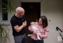 Couple with baby on doorstep smiling at baby environmental portraits Matt Payne