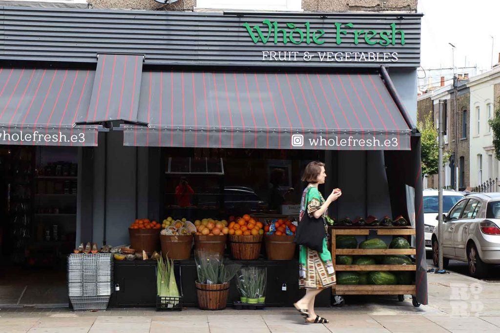 A woman walking past Whole Fresh on Roman Road in Bow, East London