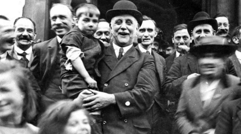 Labour MP George Lansbury in a crowd of people and holding a young boy