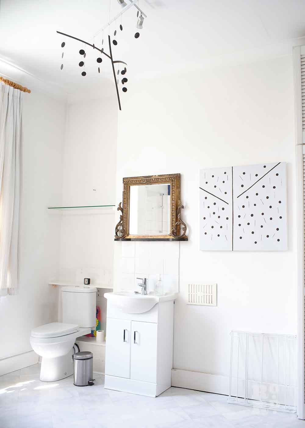 Art hanging in a white bathroom, the home of Bow artist Alice Sielle.