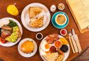 Fry-ups, breakfast sandwiches, avocado on toast and coffee sit on a table during brunch at Breakhouse Café