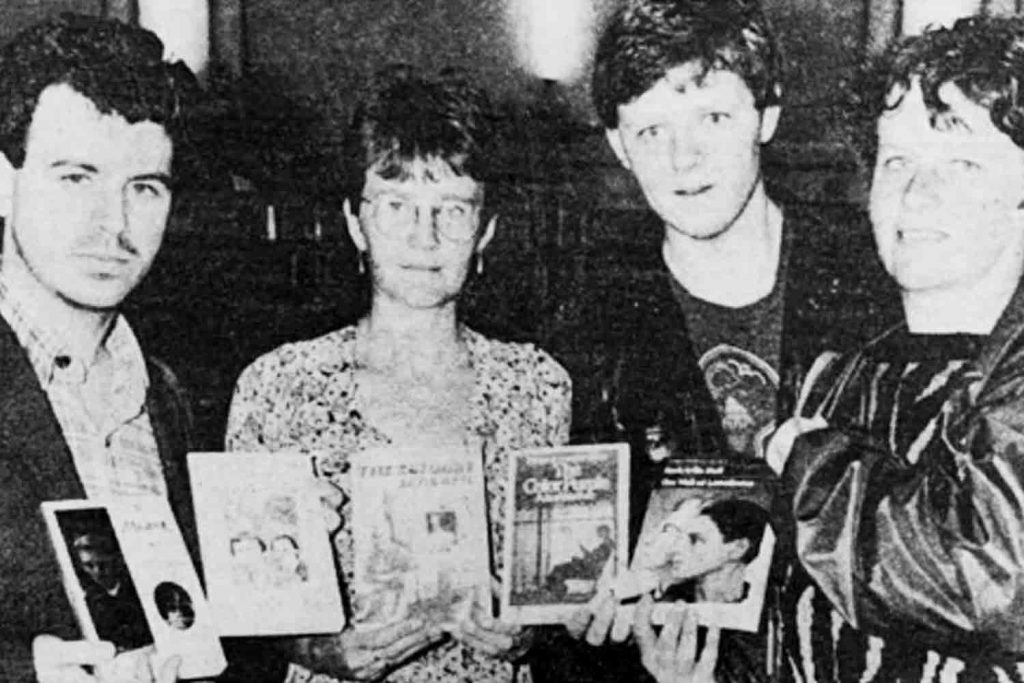 Black and white newspaper image of Chief librarian Anne Cunningham (centre left) receiving the books including The Colour Purple, with campaigner Paul Barlow (left).