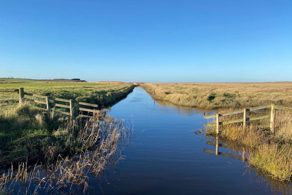 A stream of water cuts through the salthous marshes in Norfolk, a traditional East End seaside holiday