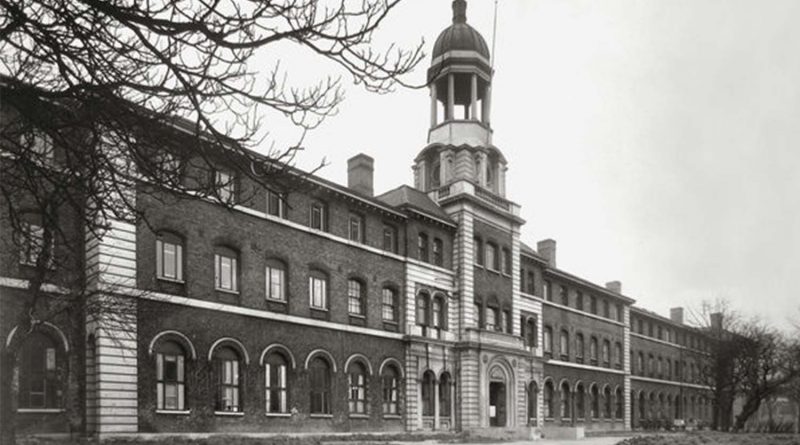 A black-and-white photograph of Stepney Union Workhouse on a grey, overcast day. Leafless trees in the foreground.