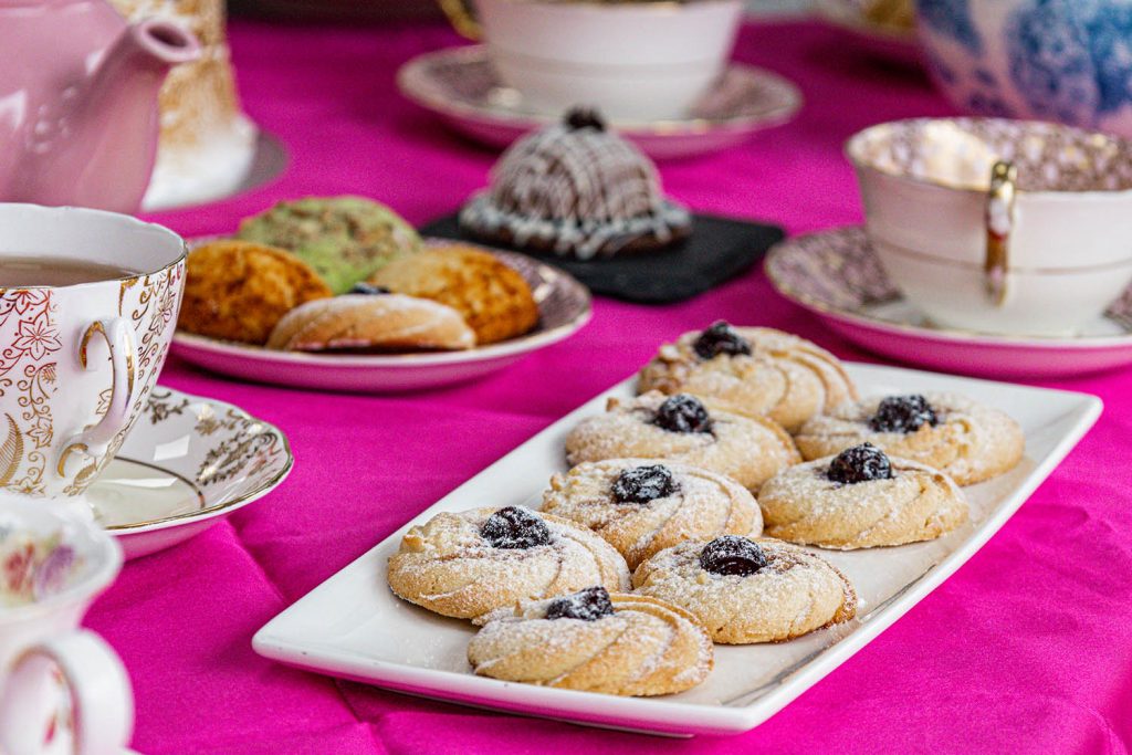 Tray of biscuits with tea in the background on a fuchsia tablecloth