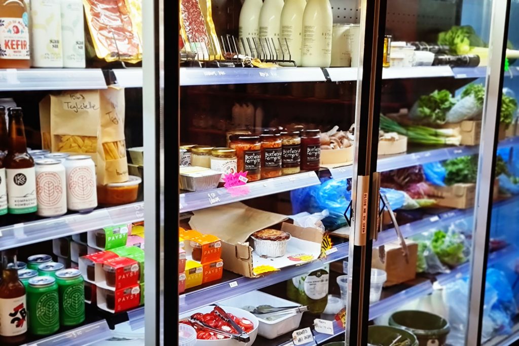 shelves of meat and dairy in a fridge, Tuck Shop, Fish Island, East London.