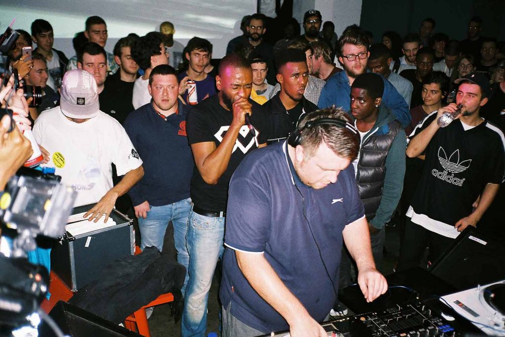 DJ Slimzee plays at Boiler Room set to a group of fans with an MC supporting him.