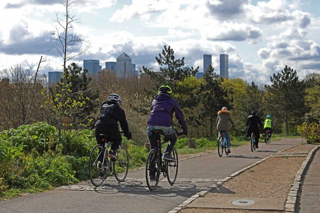 Five women cycling along a path with skyscrapers on the horizon
