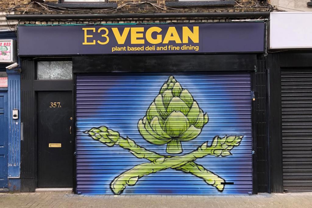 Asparagus art on shop's blue shutters, E3 Vegan, Roman Road, Bow, East London
