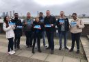 A group of people holding up Conservative posters/flyers in front of the River Thames in Tower Hamlets, East London