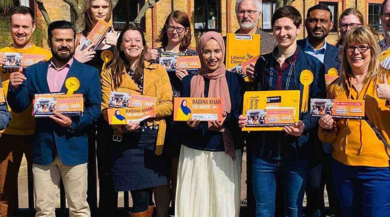 A group of people outside a building holding up Liberal Democrat leaflets in Tower Hamlets, East London.