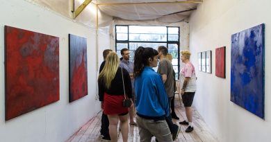A group of people in a room looking at art on white walls
