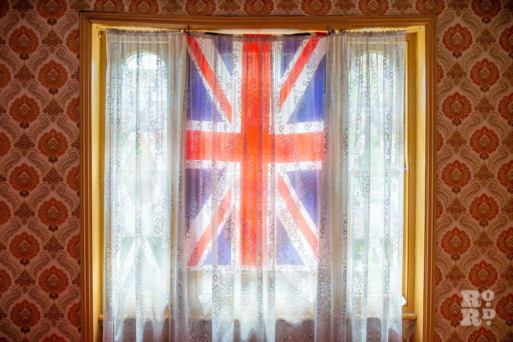 A Union Flag and net curtain covering a window on a house in Lichfield Road, Bow, East London