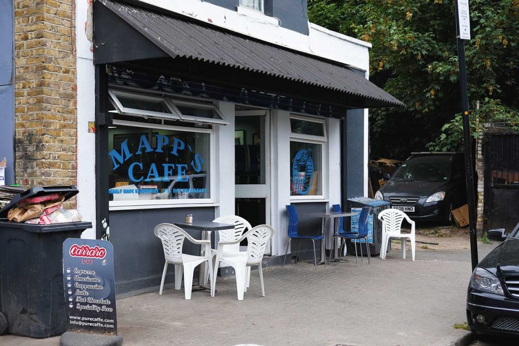 Mapps Cafe in Hackney Wick, with blue and white chairs, metal tables and cars parked around