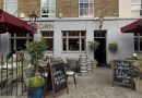 the exterior shot of a pub with beer barrels sitting outside, Coborn Street, Mile End, East London