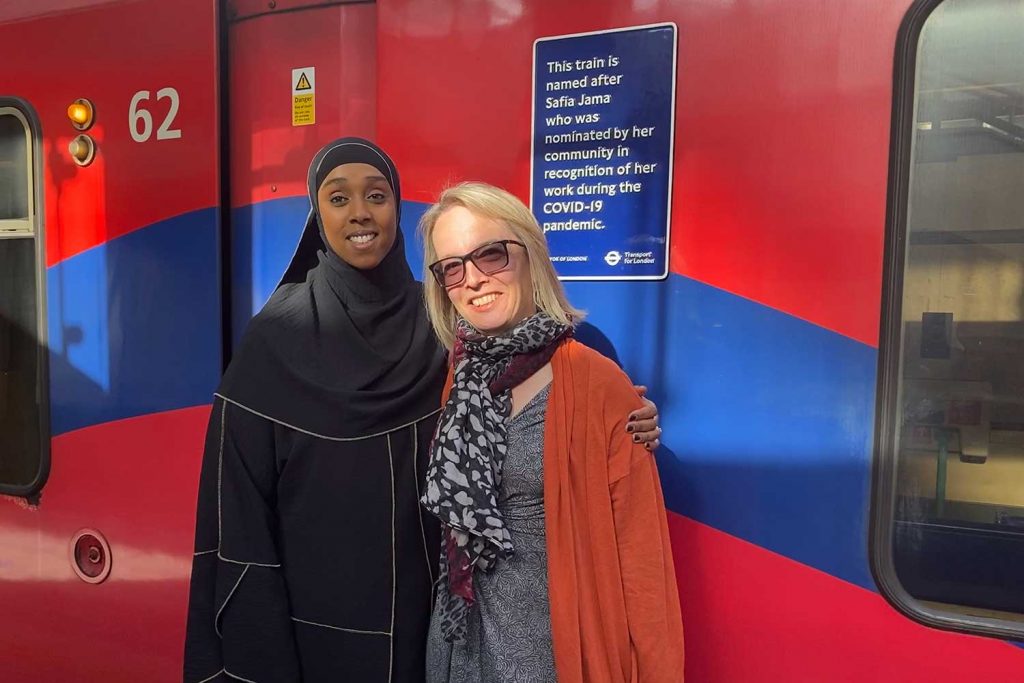 Safia Jama and Florence Perdrield in front of the DLR train named after Safia Jama in Stratford, East London