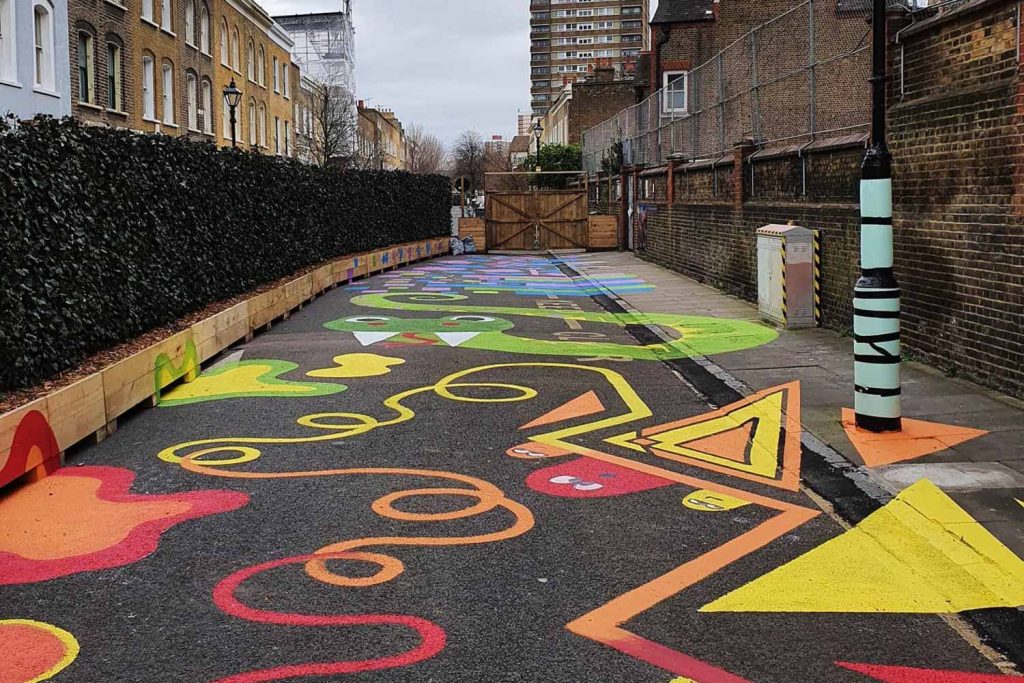 The inside of Chisenhale Primary School's Play Space with multi-coloured artwork on the pavement and road in the play space