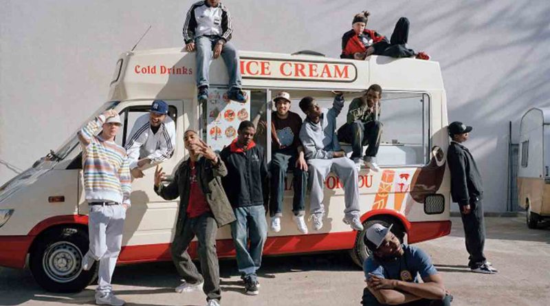 Photograph of grime rapper Wiley by an ice cream van with his entourage of ten.