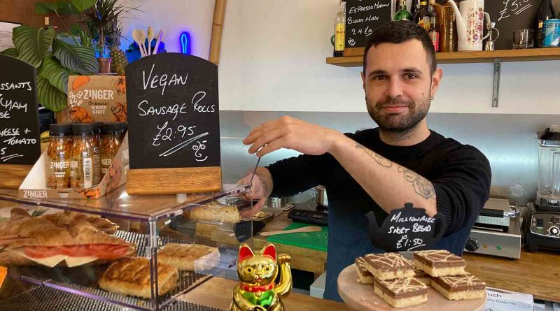Alex Navarro serving vegan sausage rolls behind the counter at Jungle Electric cafe.