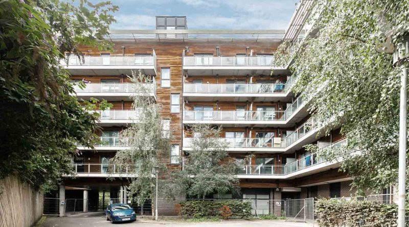 Outside shot of Diagoras House in Bow, East London. A five-storey apartment block with balconies and overhanging trees.