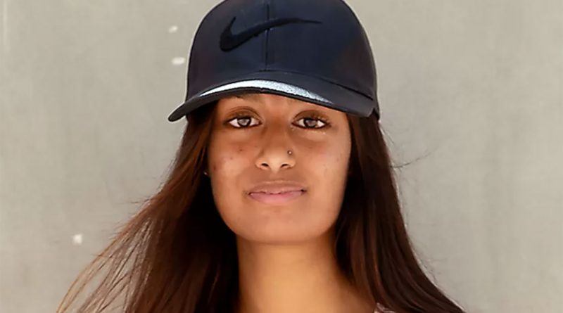 Bethnal Green's Shamima Begum wearing a cap for a headshot photo on a white background. She has a silver nose piercing, red hair and a white top.