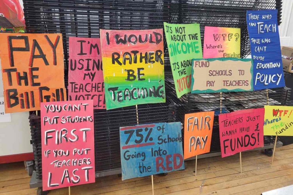 Protest signs made by teachers of various colours and slogans.