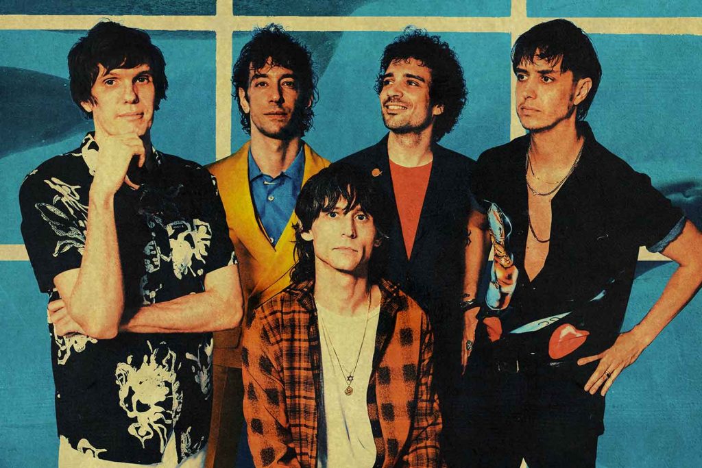 The Strokes band of five posing for a photo against a light blue tiled background.