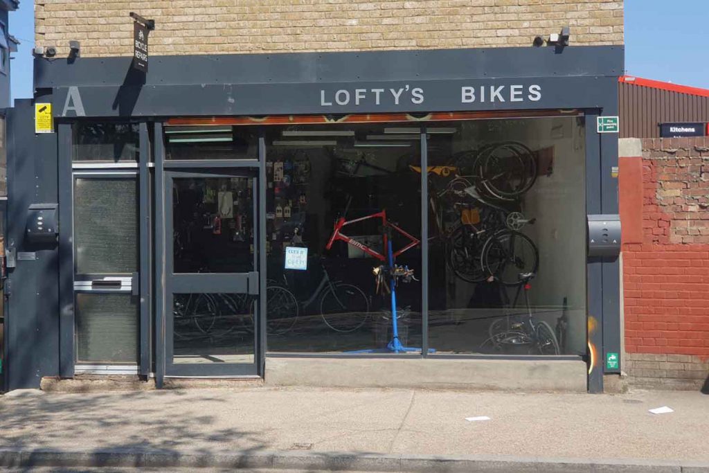 A small bike shop with a window showing bikes hanging on the walls