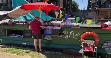 Man browses through records at a record shop that is a barge in the sun.