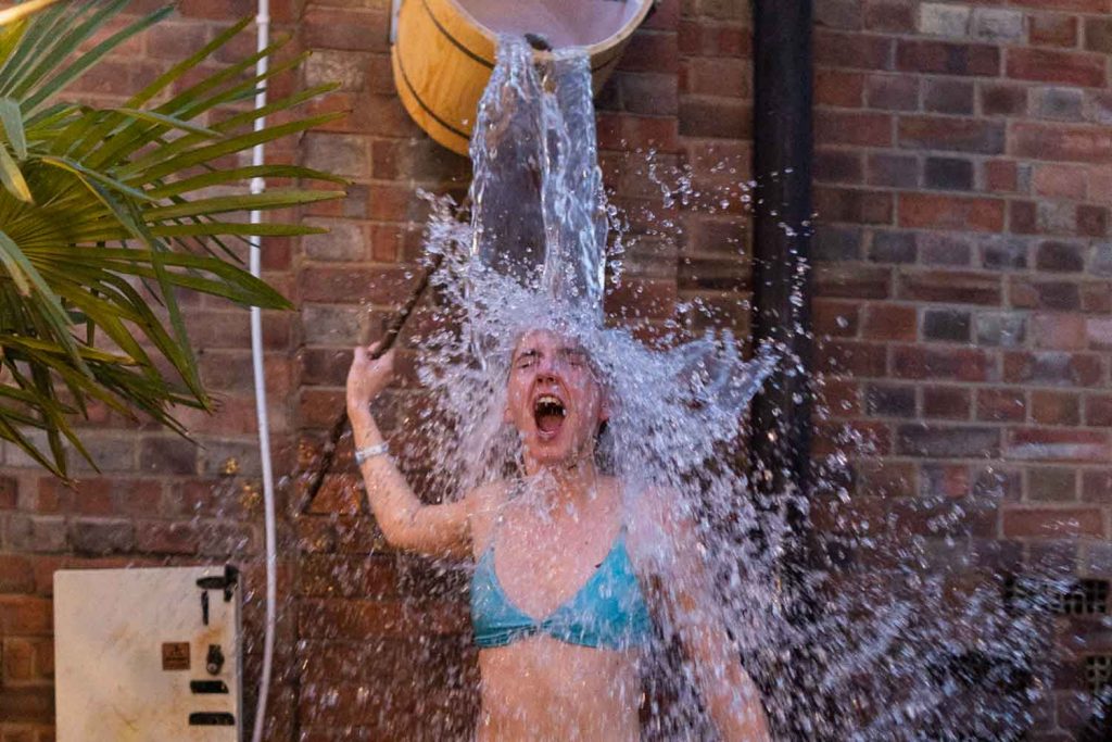 Woman has cold bucket shower at Hackney Wick's Community Sauna Baths.