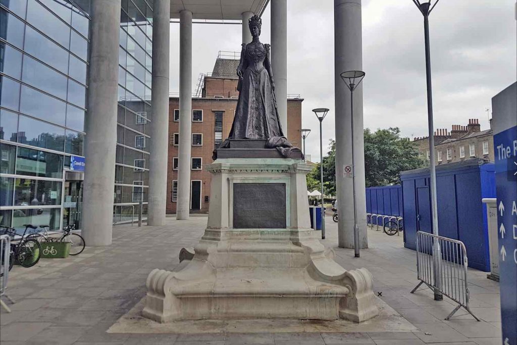 Statue of Queen in royal clothing outside a hospital on a cloudy day