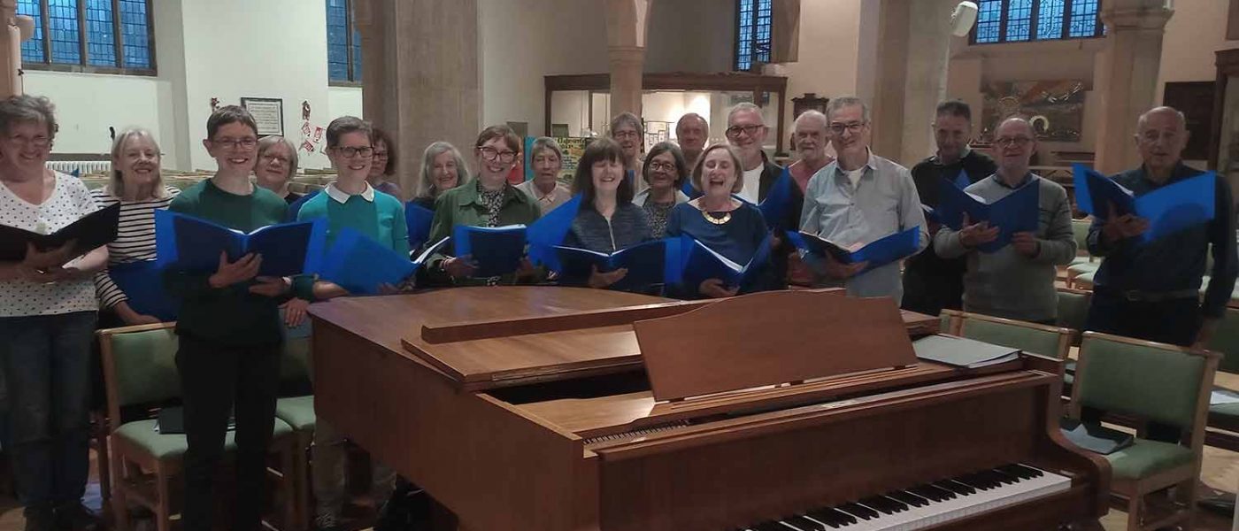 Aldersbrook community choir singing behind a piano in a church.